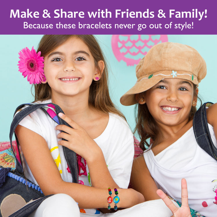 Two girls friends, smiling and wearing handmade bracelets from the Chalk and Chuckles DIY kit – perfect bonding and gifting activity for kids.